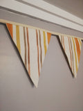 Stripy fabric bunting, mustard, yellow and shades of brown.